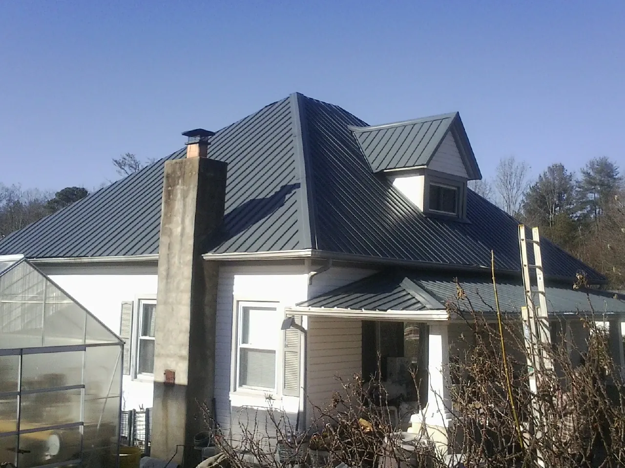 Dark blue standing seam metal roof on a white farmhouse with dormer — Slate & Tile Roof Repair by Roofing Brothers in Moon