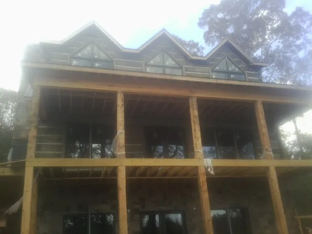 Dormers and porch framing on a large log home under construction — Roof Coating work by our crew in Moon