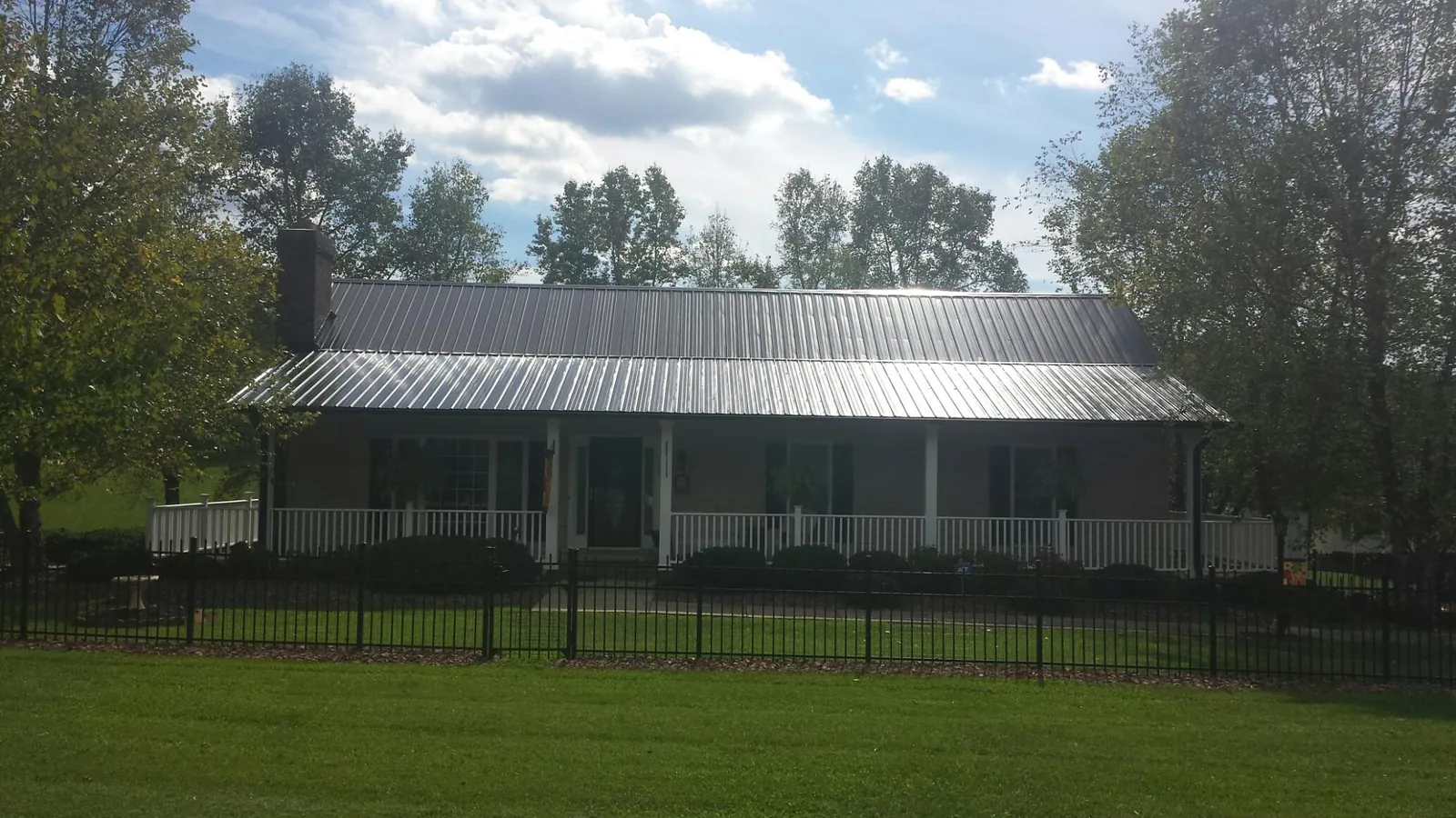 Gray metal roof on a brick ranch with a full width front porch in Moon