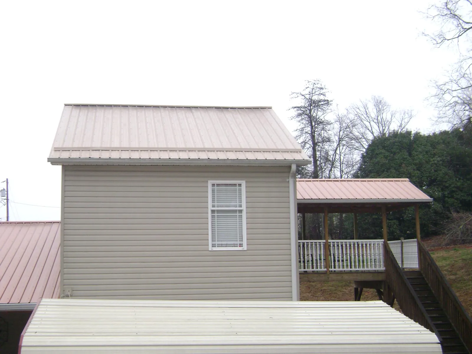 Tan metal roofs on a two story addition and attached porch, from a Roof Replacement job in Moon
